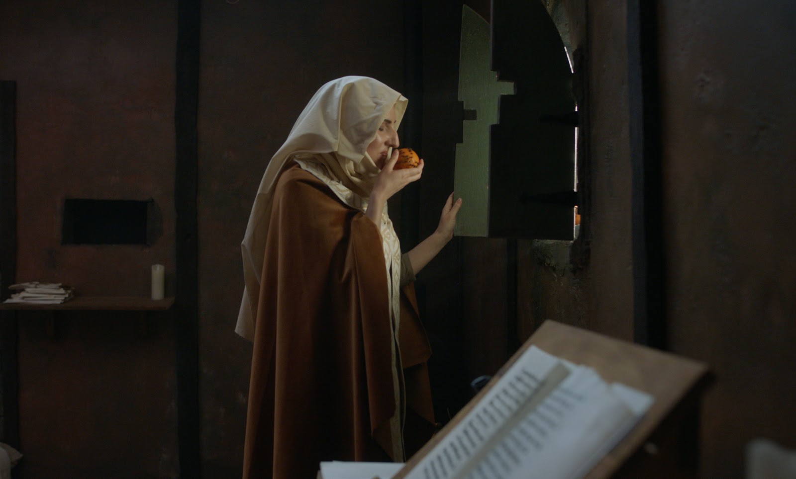 Tessa Strain as Julian of Norwich enjoys a Christmas orange on set in Ridgewood, Queens.