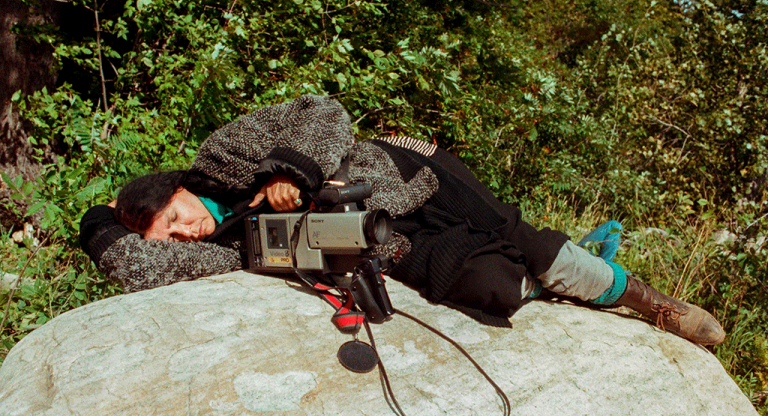 Alanis Obomsawin rests on a rock beside the Lake of Two Mountains, Kanehsatake, 1990. / Photo: John Kenney 